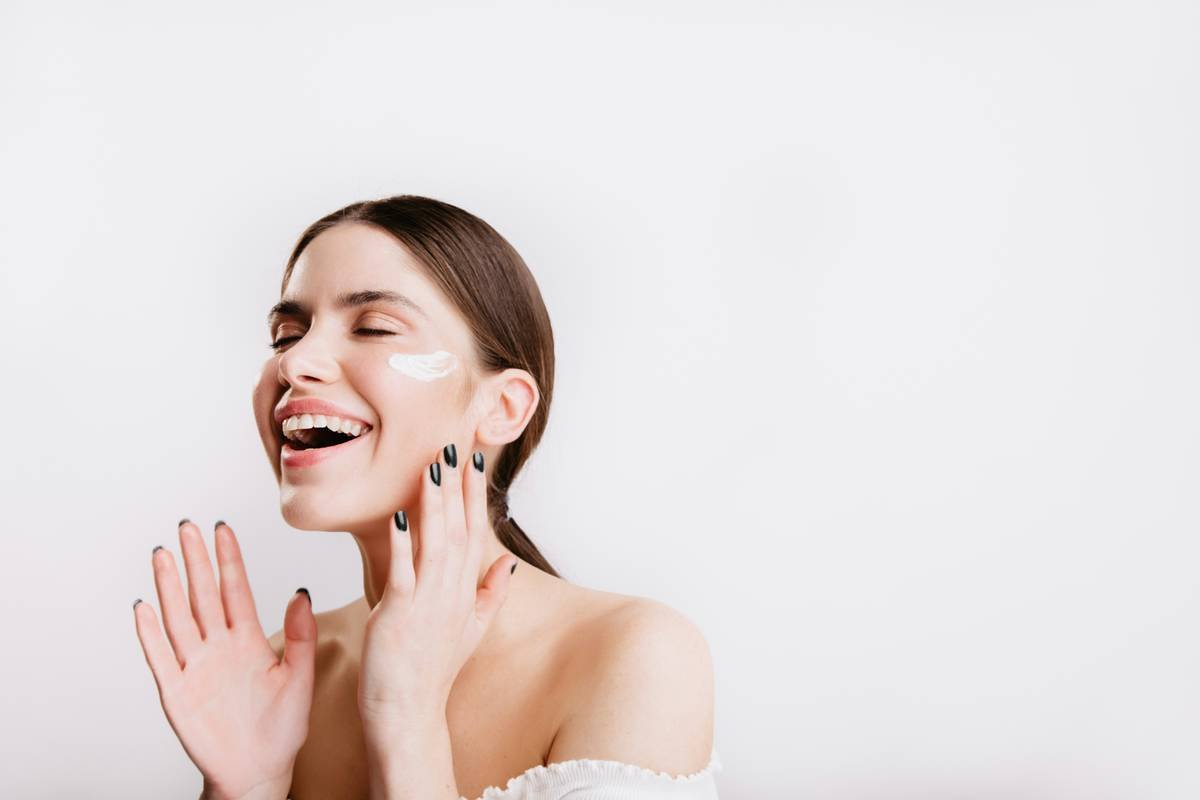 Applying lightweight tinted moisturizer Laura Geller with fingertips for natural finish