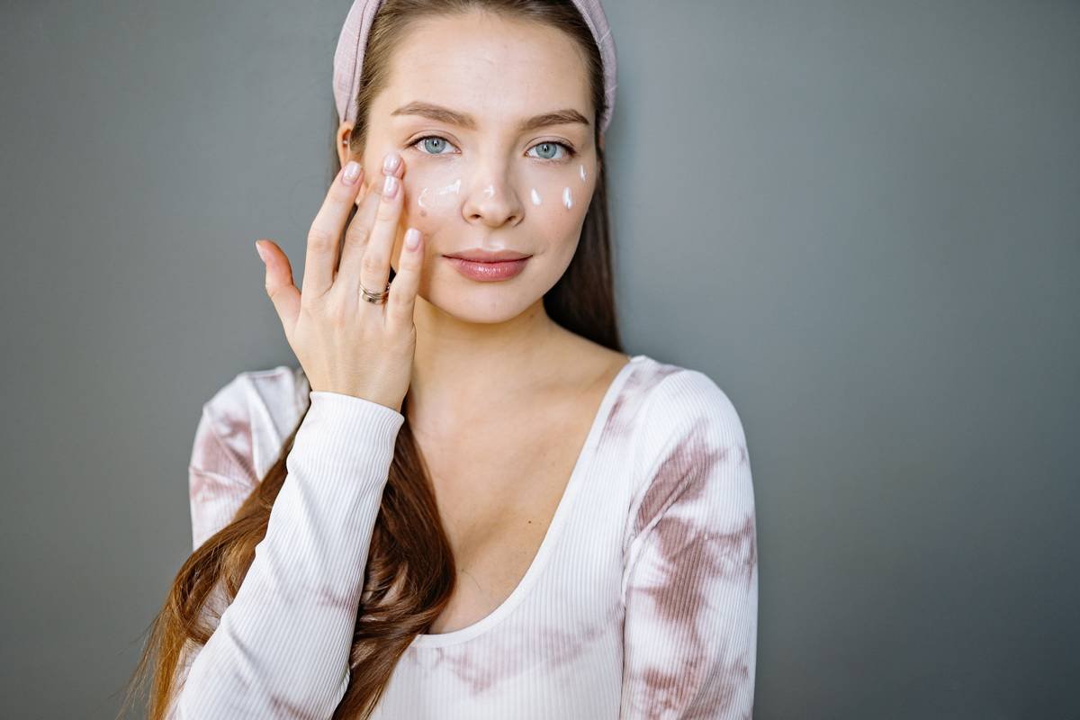 Woman applying tinted moisturiser for mature skin with fingertips for seamless blend